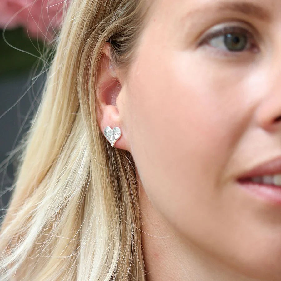 Close-up of a woman wearing heart-shaped earrings with a blurred background