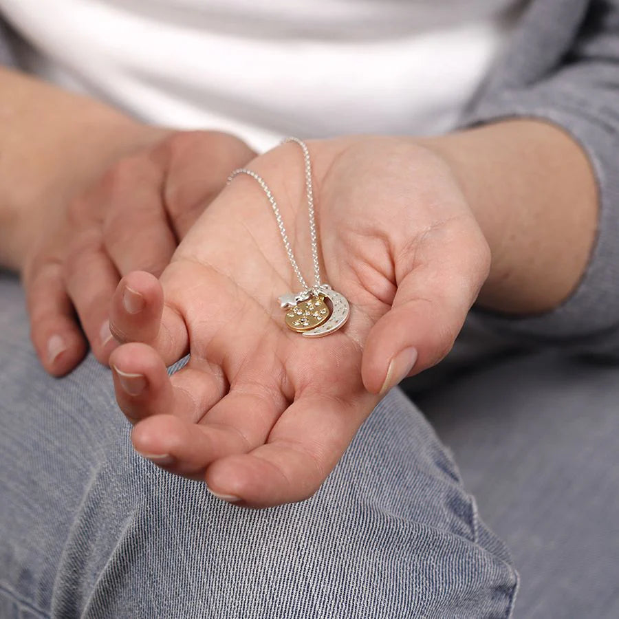 Person holding a silver plated necklace with a pendant in their palm