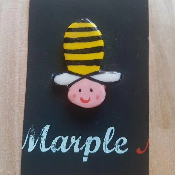 Bee-shaped pin on a black card with 'Marple' text