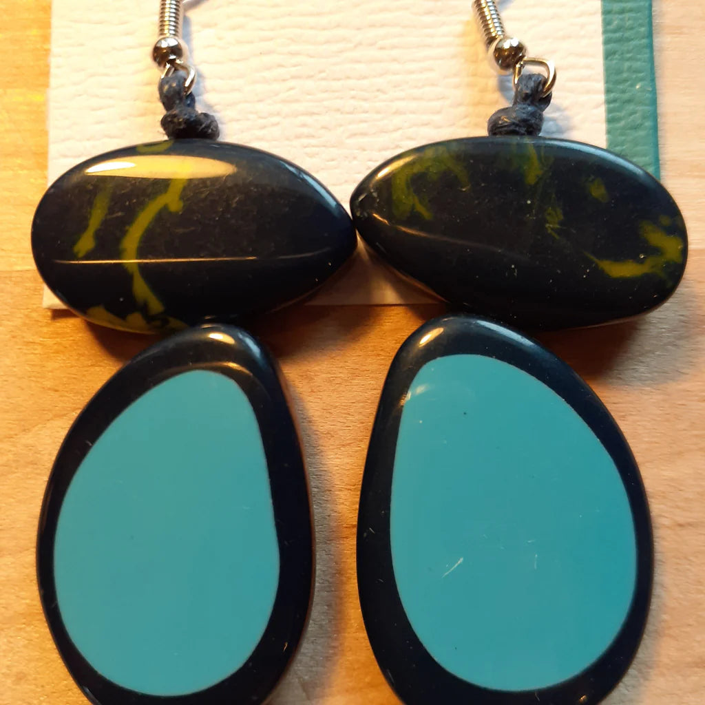 Pair of earrings with black and green marbled design on a wooden surface