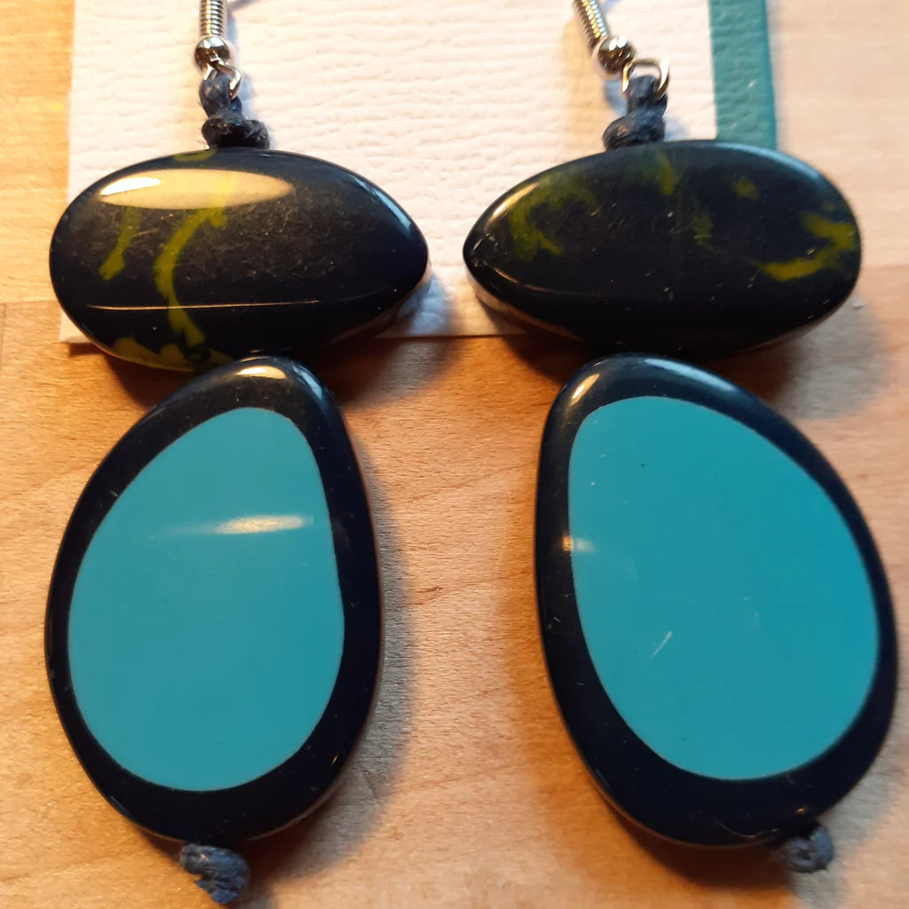 Pair of earrings with black and blue oval stones on a wooden surface