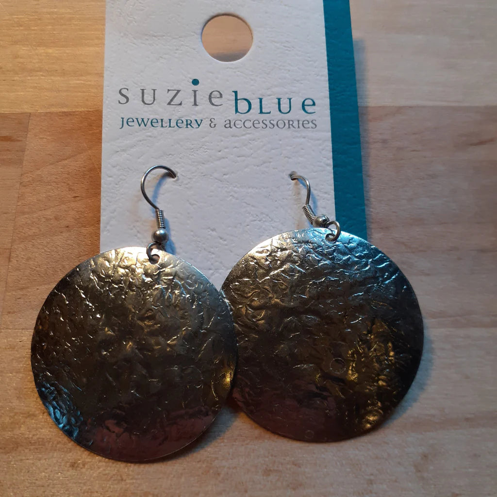Silver textured earrings on a wooden surface with 'suzie blue' jewelry card.