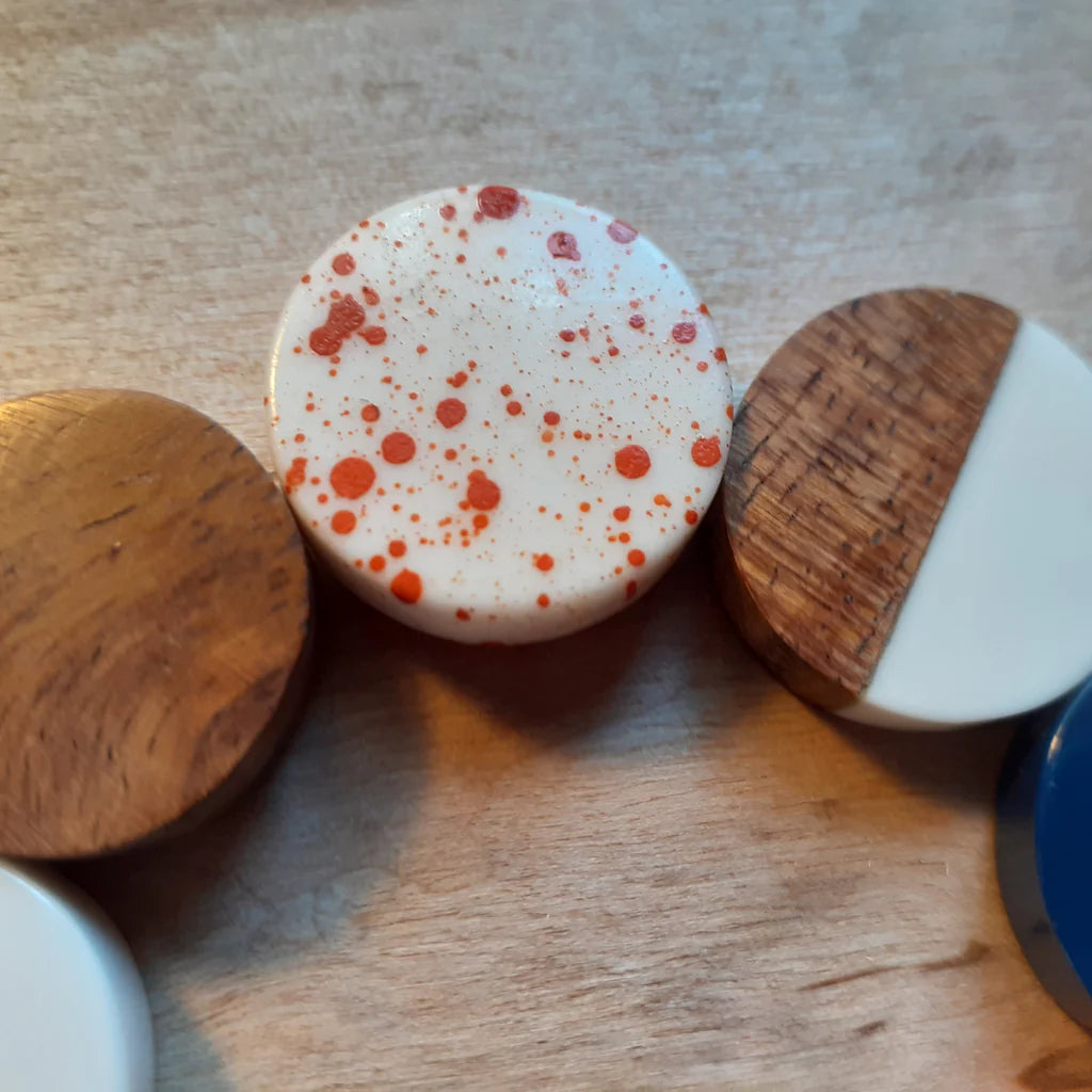 Three cylindrical objects with wooden and ceramic parts on a wooden surface