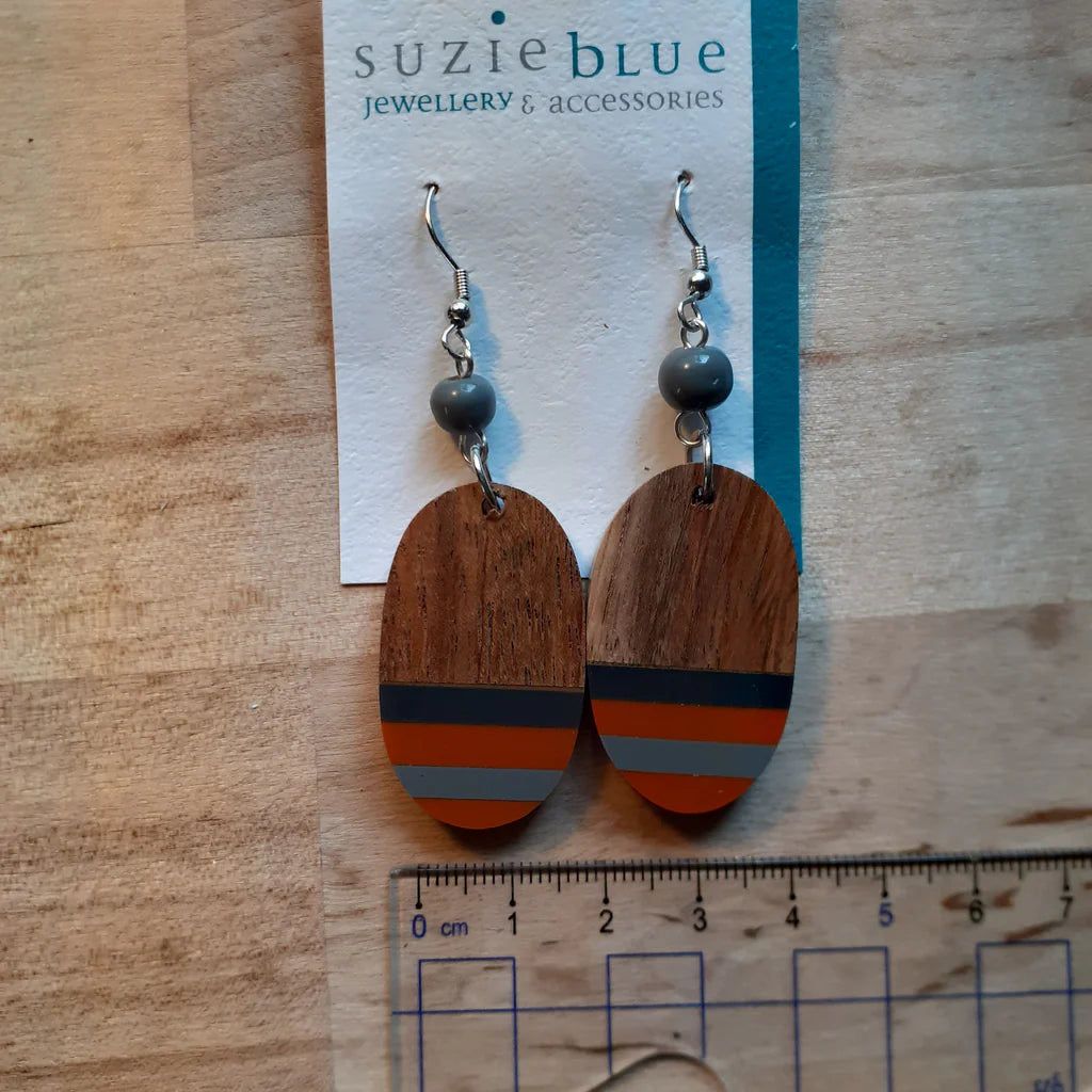 Wooden earrings with gray beads on a 'Suzie Blue' card, displayed on a wooden surface with a ruler for scale.