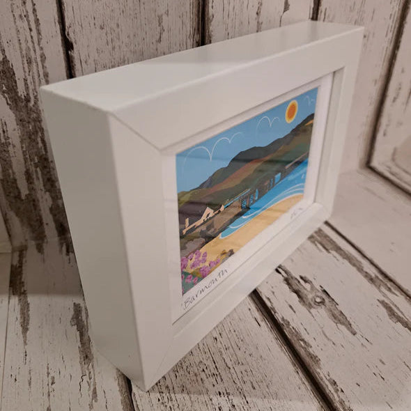 Framed artwork of a scenic landscape on a wooden surface