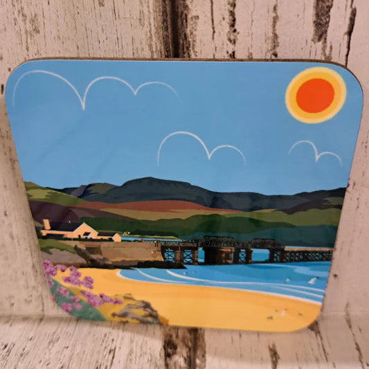 Coaster with a scenic design of mountains, sun, and landscape on a wooden surface