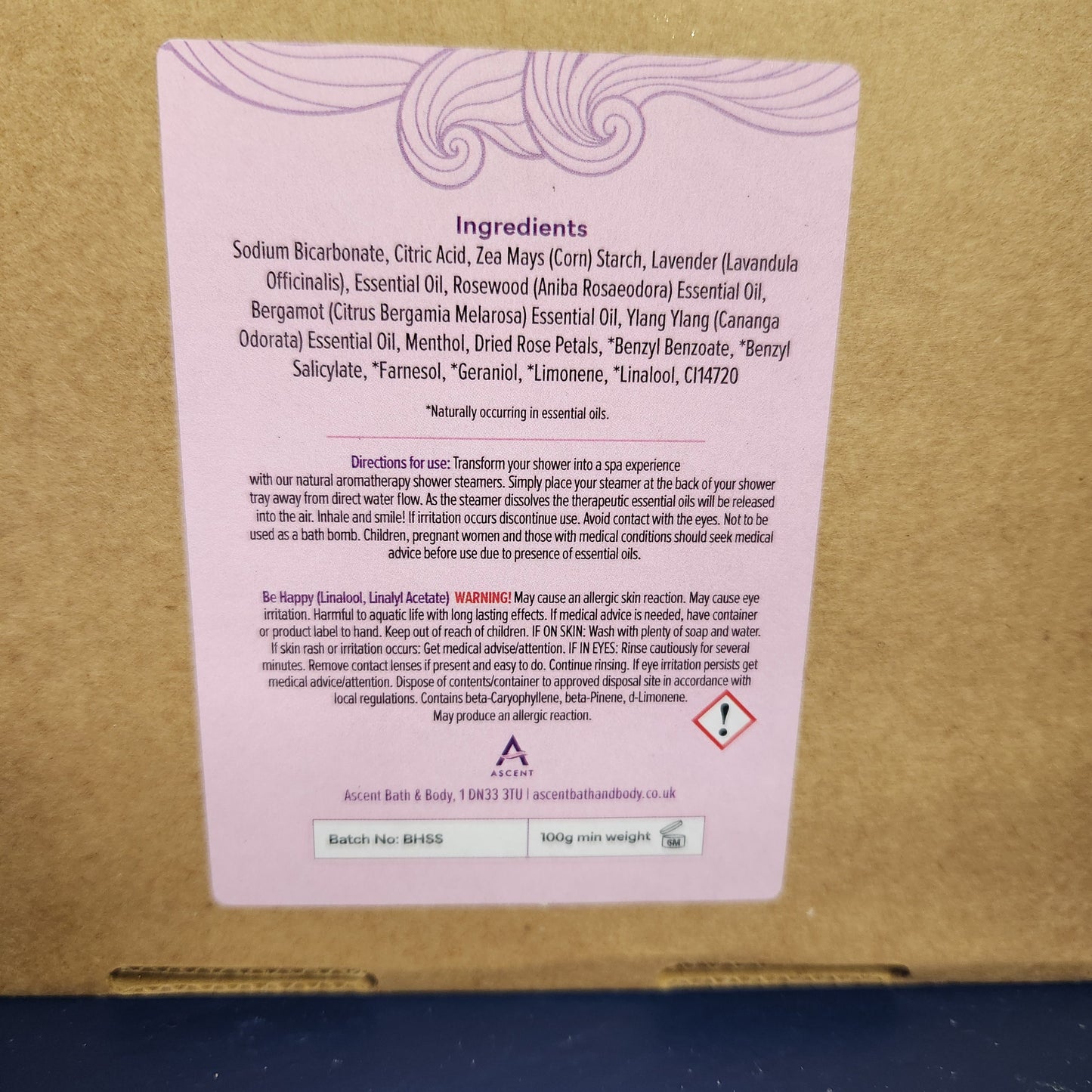 Cardboard box with a pink label containing text and symbols on a blue background