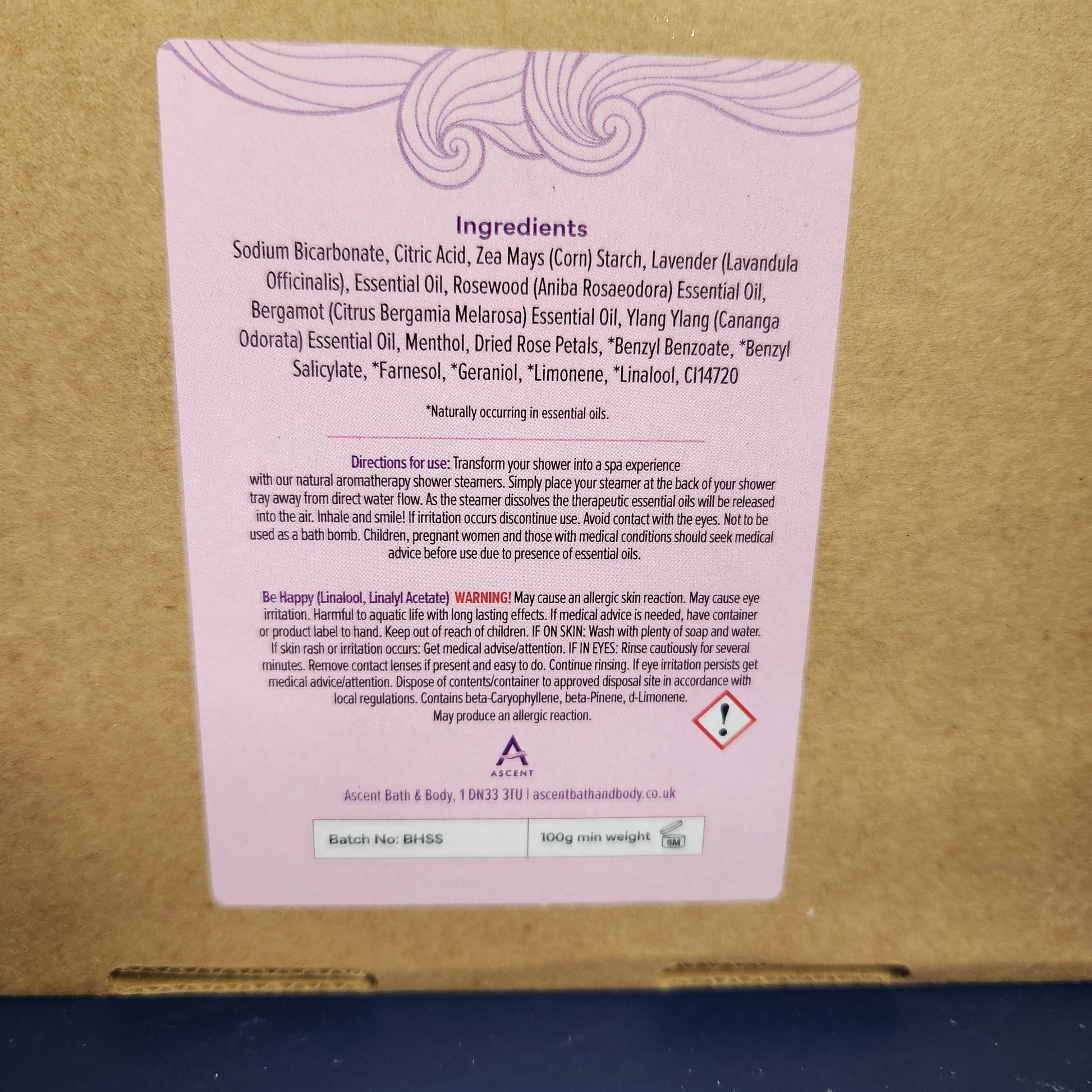 Cardboard box with a pink label containing text and symbols on a blue background