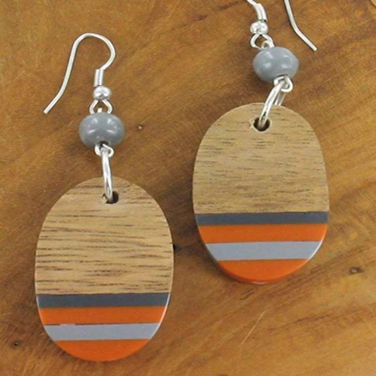 Wooden earrings with colorful stripes on a wooden surface