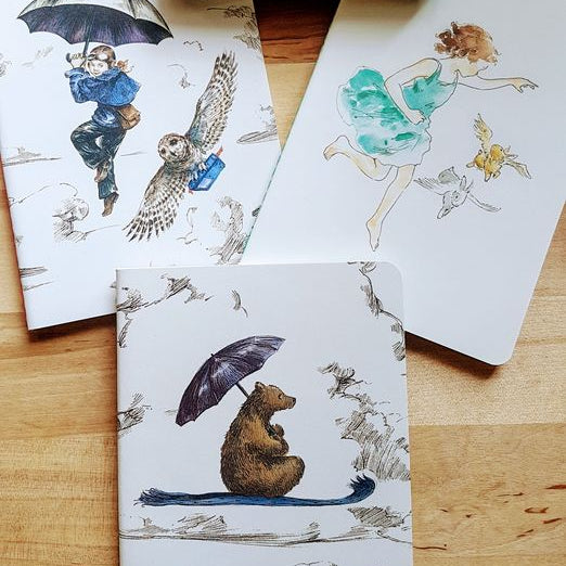 Notebook set with artistic designs on a wooden surface, featuring a 'Roger la Borde' box.