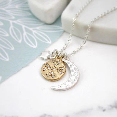 Silver plated necklace with a gold coloured pendant featuring star designs on a marble surface.