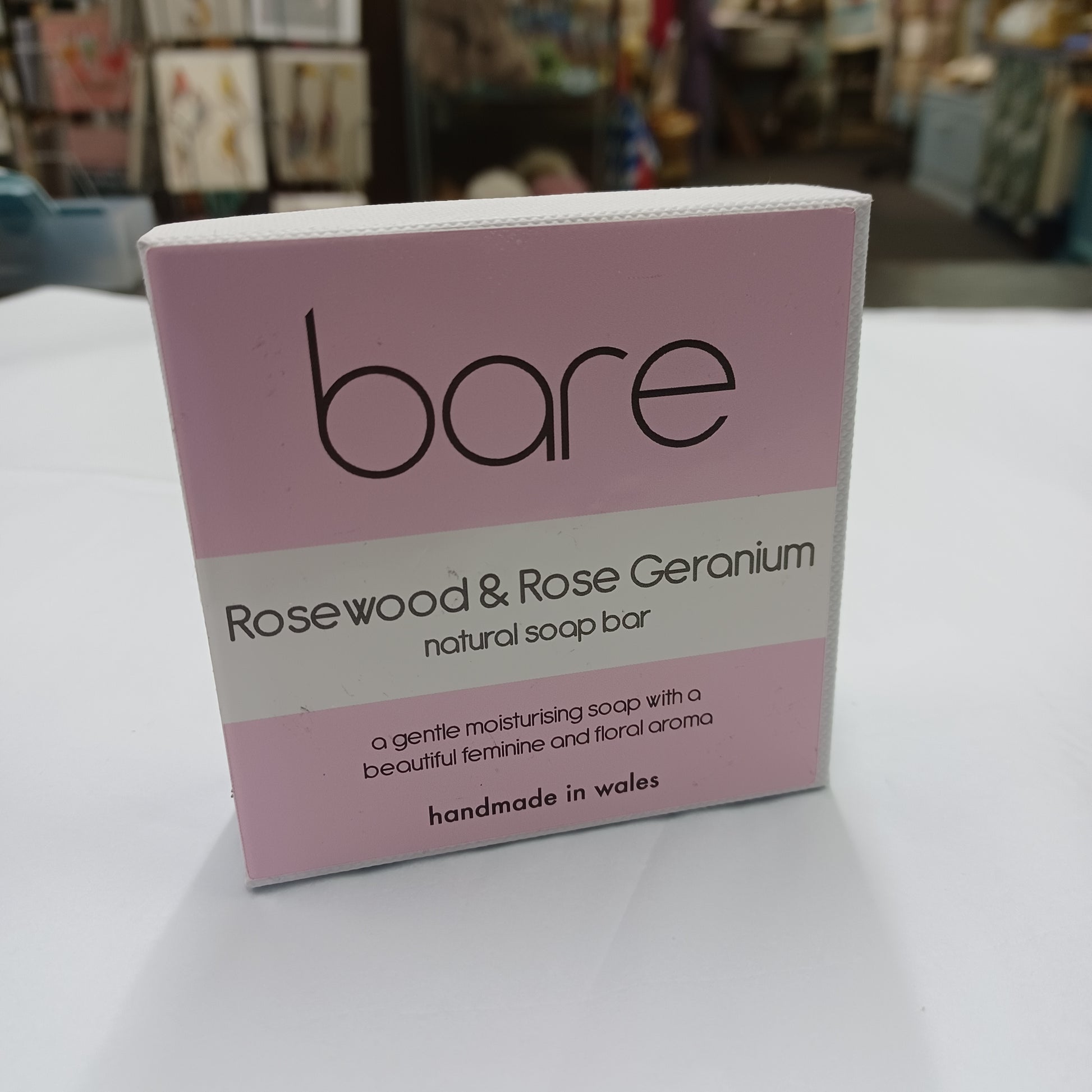 Box of bare Rosewood & Rose Geranium soap on a white surface with a blurred background