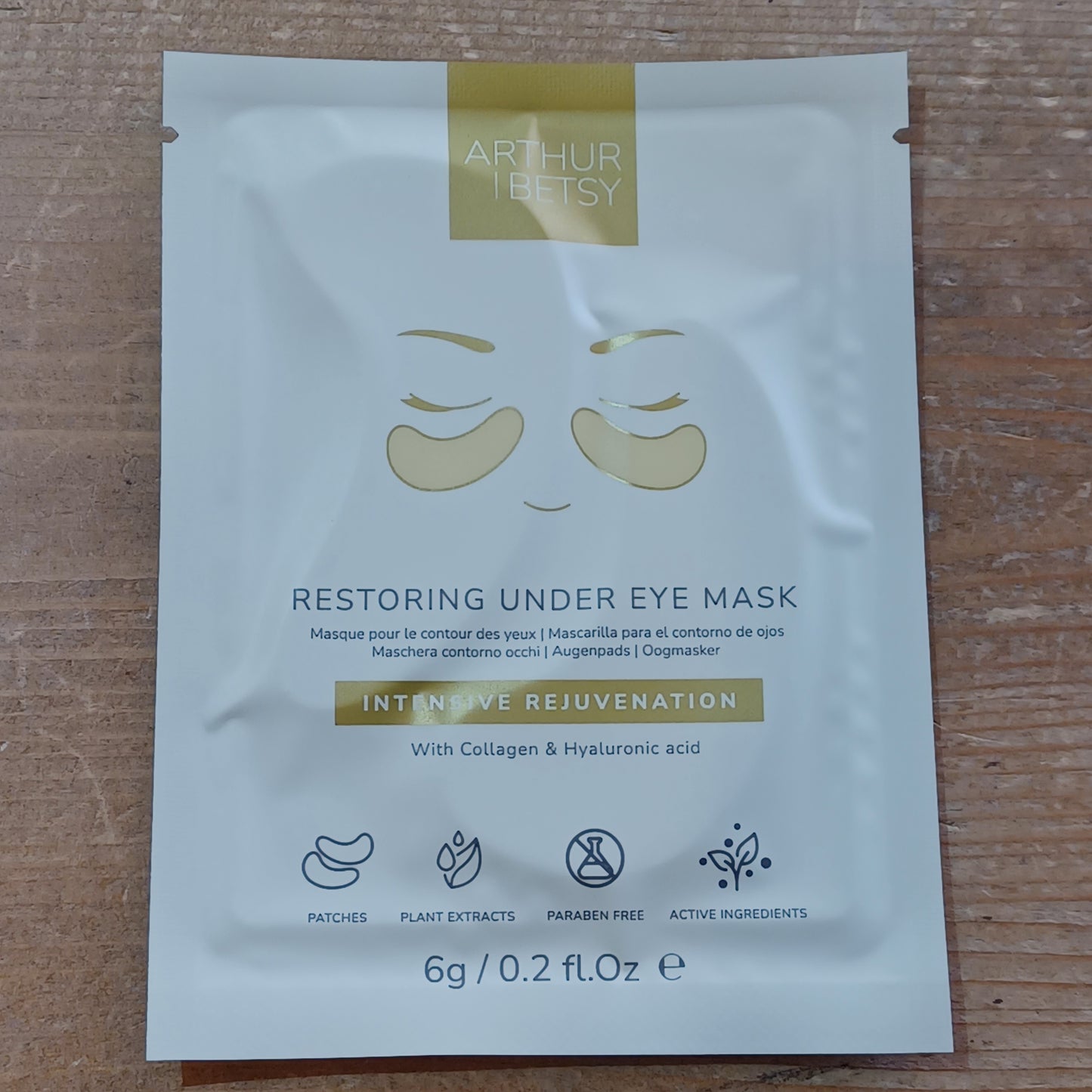 Under eye mask packaging with brand name on a wooden surface