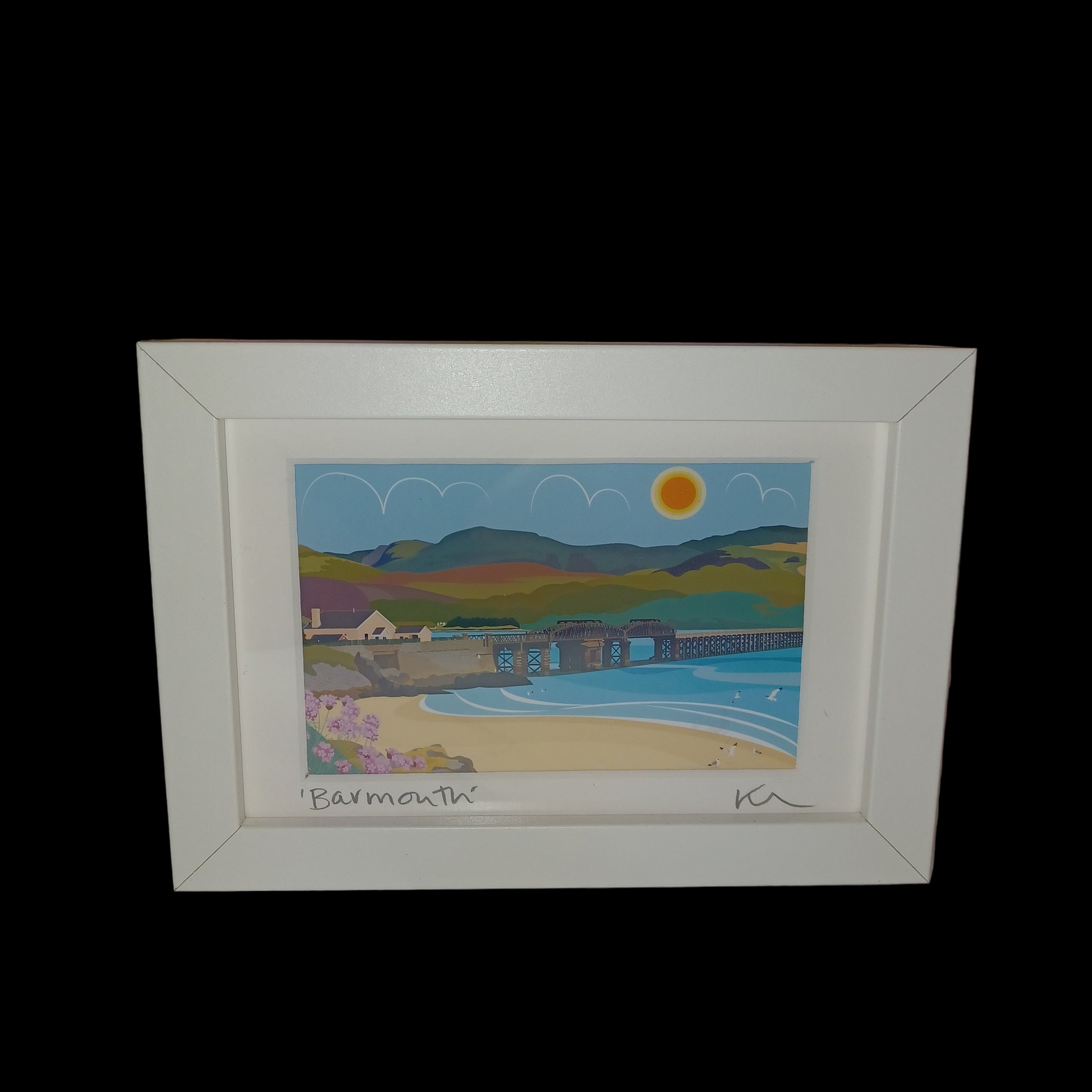 Framed artwork with a colorful landscape scene on a shelf.