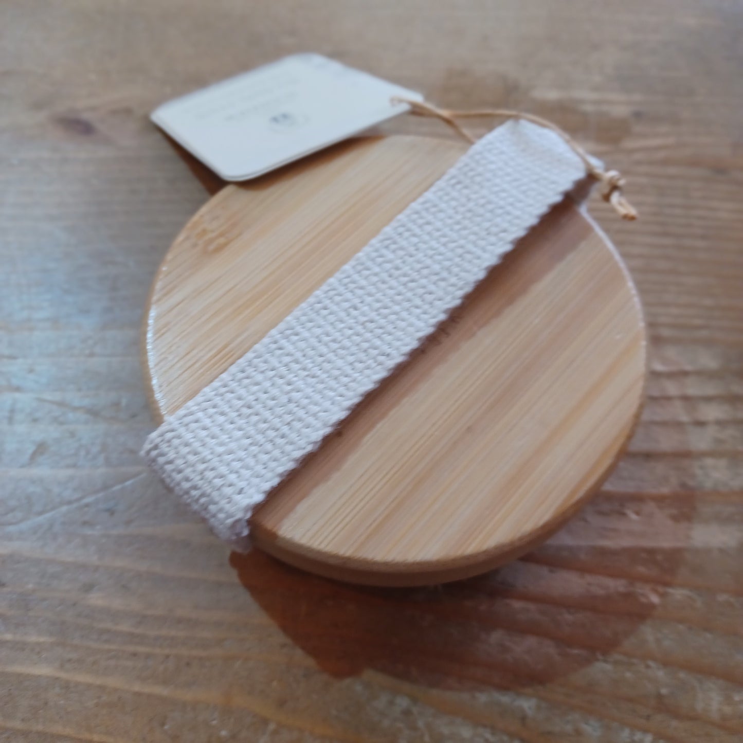 Wooden circular object with a white strap on a wooden surface