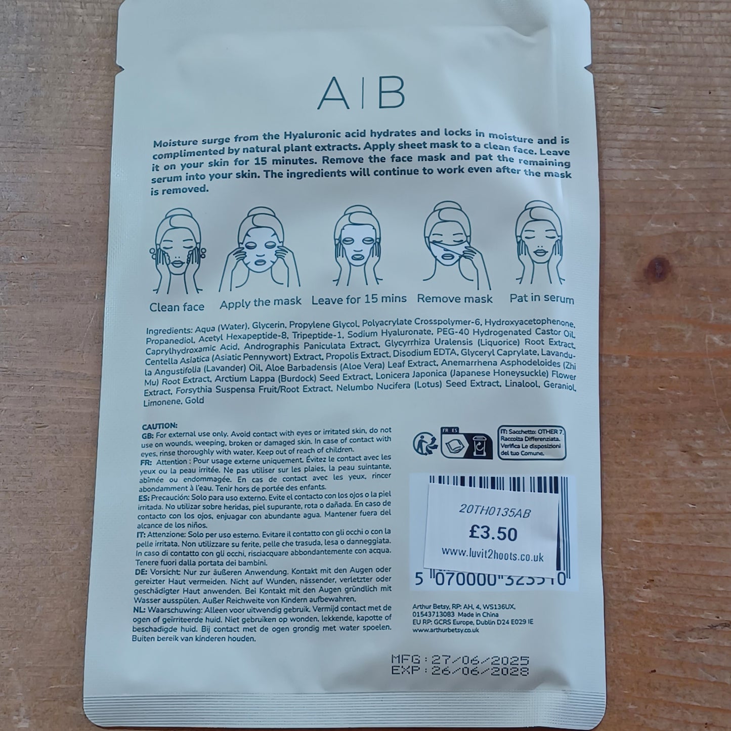 Back of a skincare mask packaging with text and barcodes on a wooden surface