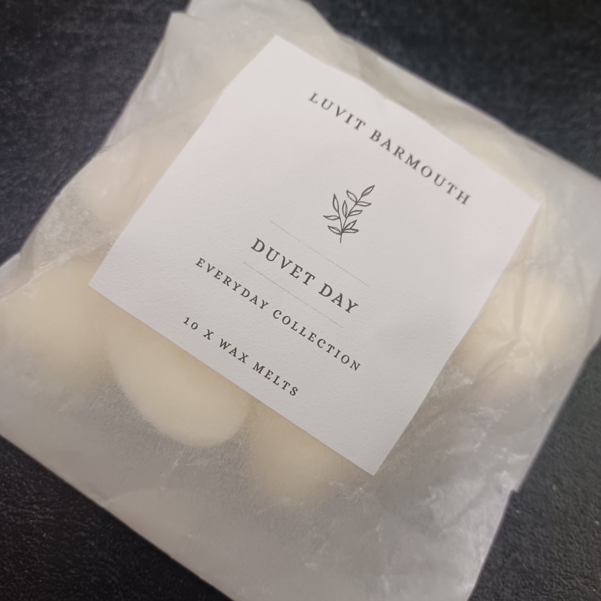 Packaged wax melts with a label on a dark surface