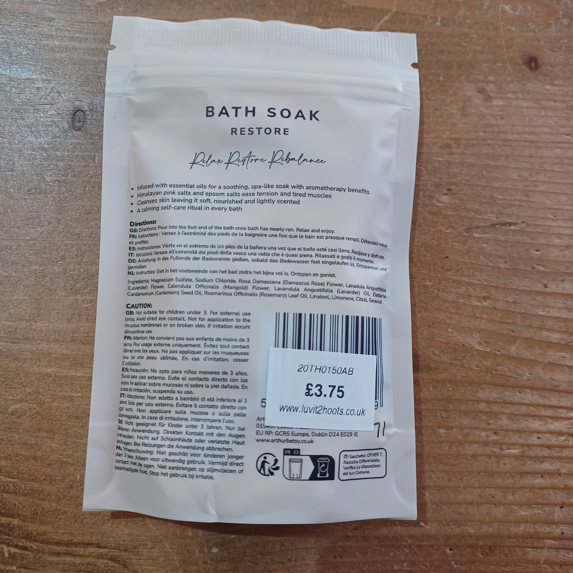 White bath soak packet with text and a barcode on a wooden surface