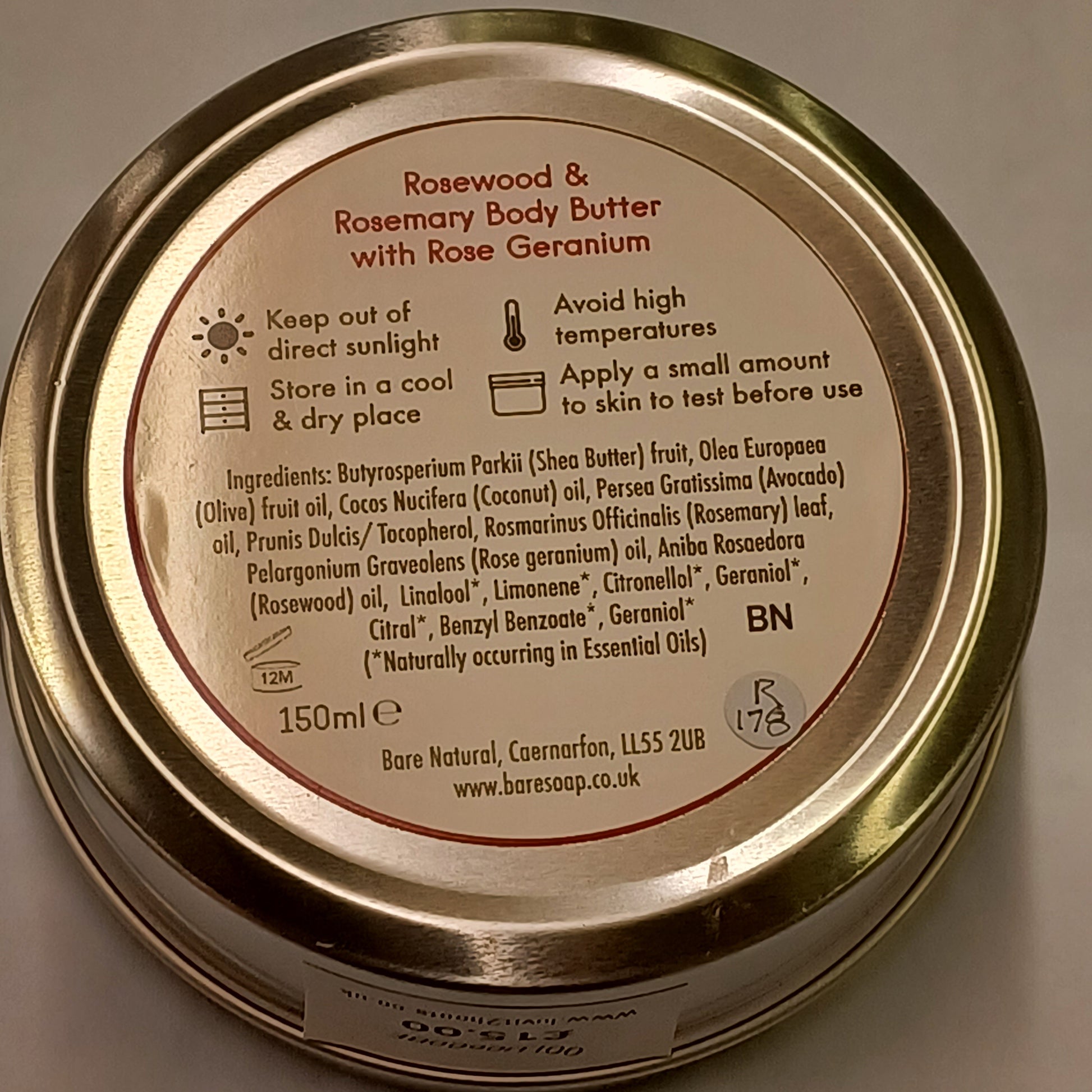 Close-up of a gold jar lid with text and branding on a neutral background